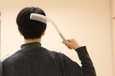 a person using long handled comb to comb hair