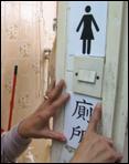 图一: 图中显示在家居厕所墙上, 张贴一个中文字「厕所」标贴, 及 一个「女士」黑色图像的标贴, 代表女厕