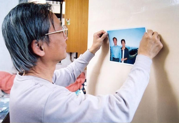 一名男士在家中墙上贴上一幅照片