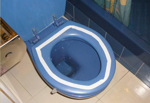 一个蓝色的坐厕，厕板上贴有围成一圈的白色贴纸