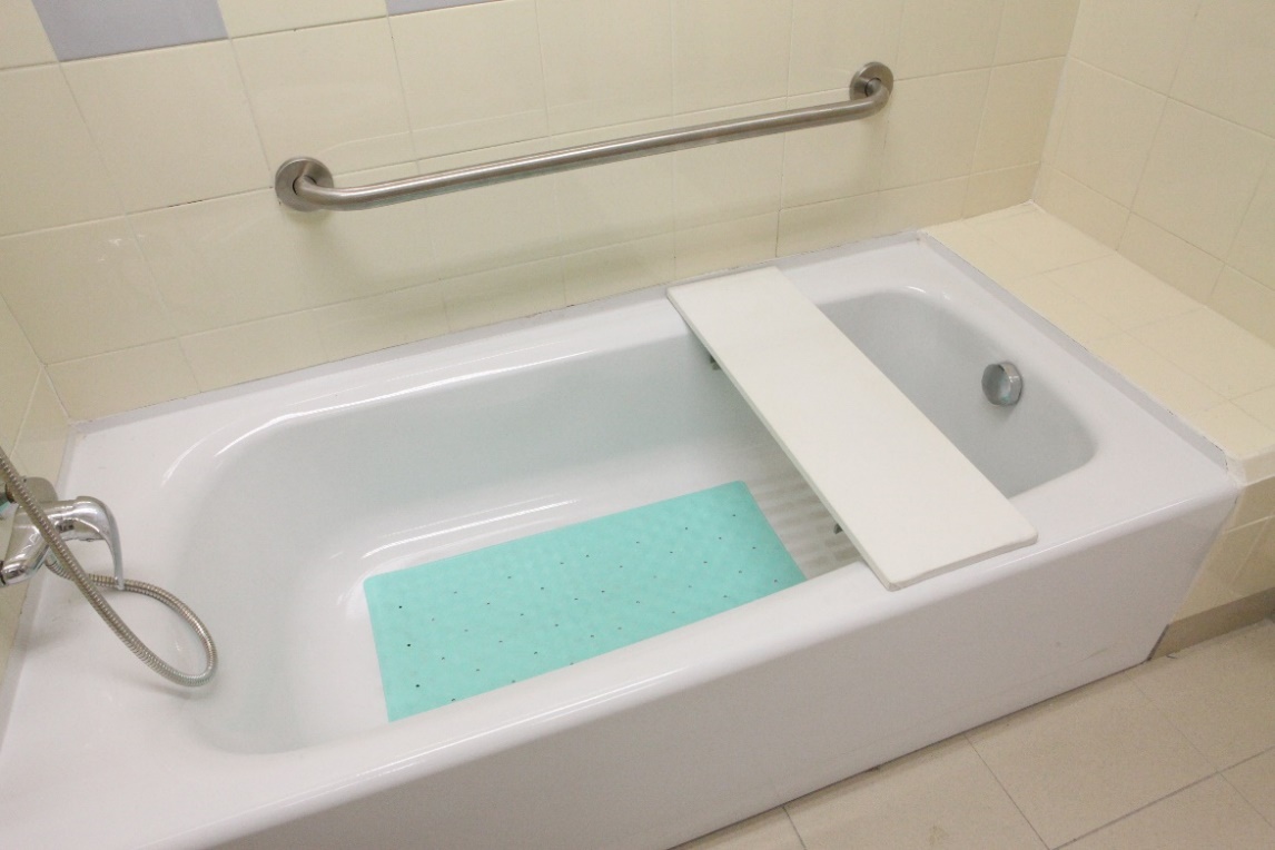 图中显示一块浴缸板放在浴缸上，浴缸板是一块长方形的板，横跨浴缸两边，浴缸板底部设有固定器用作固定于浴缸内壁。
