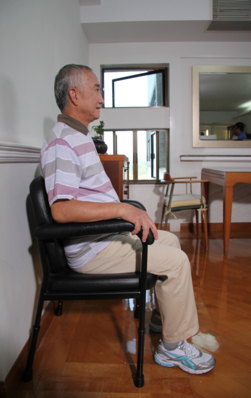 图中显示一男长者坐在高度适中的椅子上，膝关节屈曲成90度，双脚能平放在地上，及有足够背部承托。
