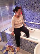 圖中顯示一位長者坐在浴缸板上進出浴缸